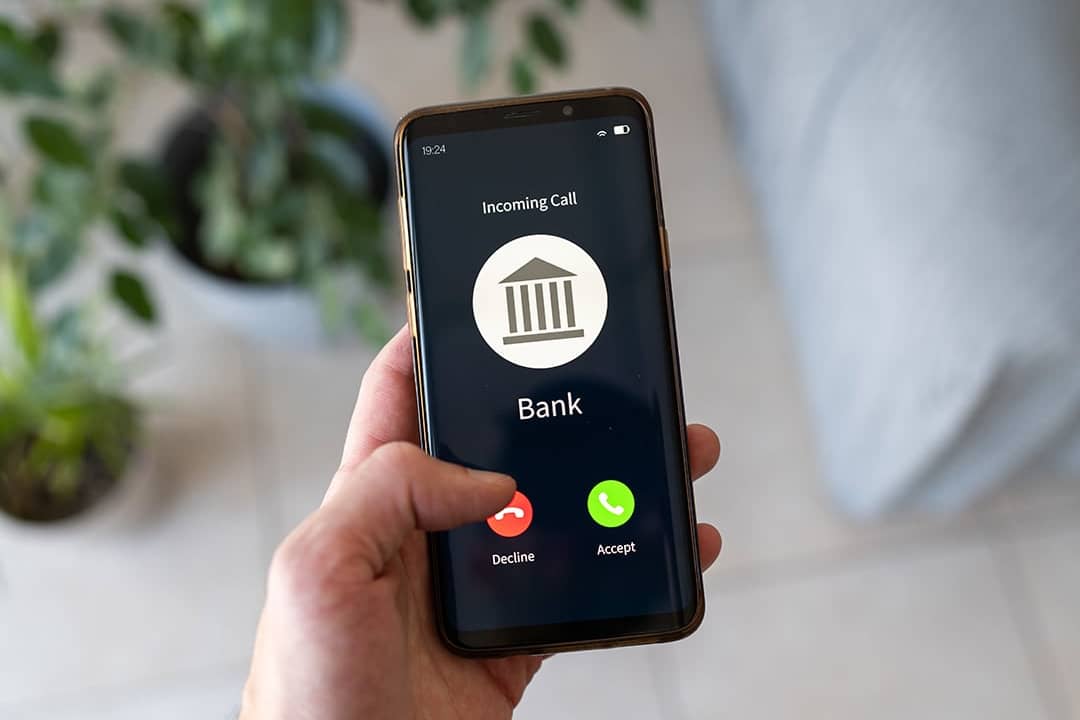 Hand holding a smartphone with an incoming call from a bank